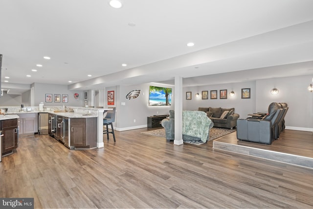 kitchen featuring a breakfast bar, open floor plan, recessed lighting, and wood finished floors