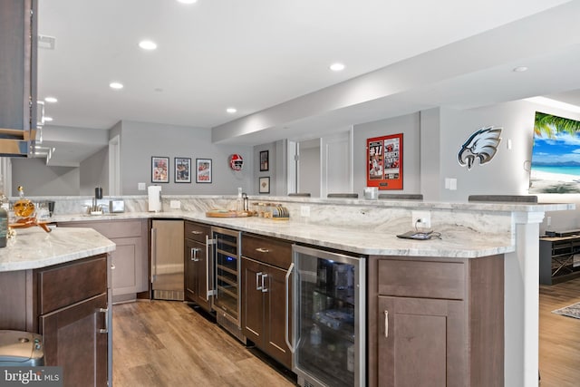 kitchen featuring light wood-style floors, recessed lighting, beverage cooler, and light stone counters