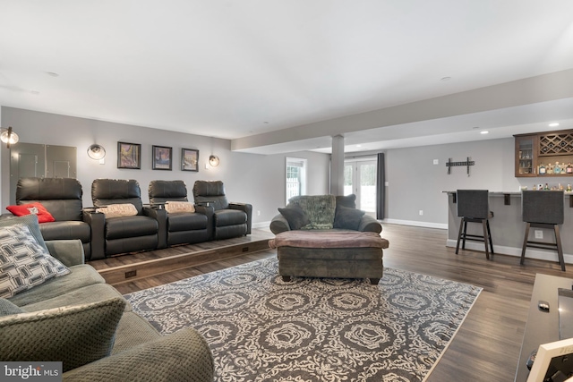 living room with a bar, wood finished floors, and baseboards