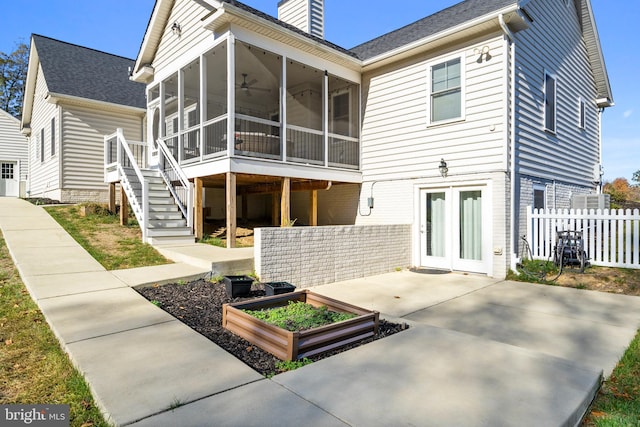 rear view of property with a chimney, a sunroom, fence, a garden, and stairs