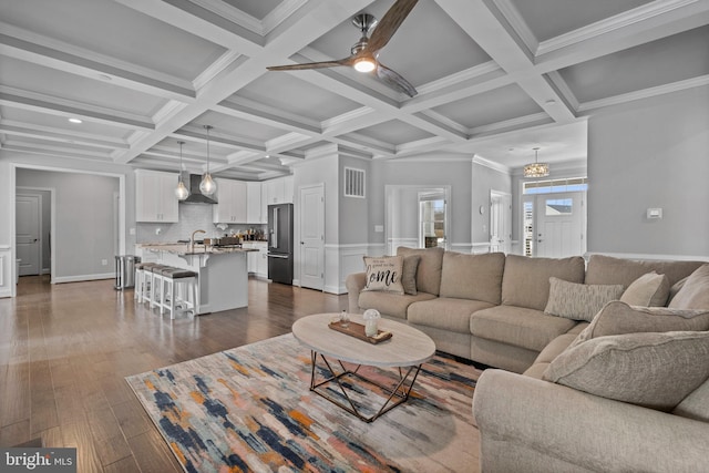 living room featuring a ceiling fan, dark wood finished floors, coffered ceiling, and beamed ceiling