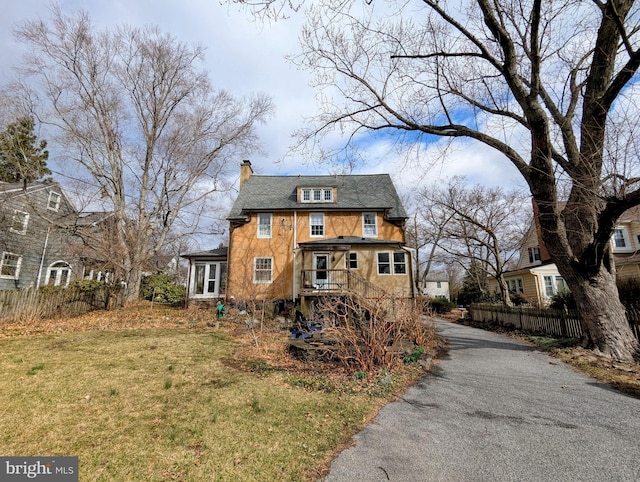 view of front of property featuring a front yard, driveway, a chimney, and fence