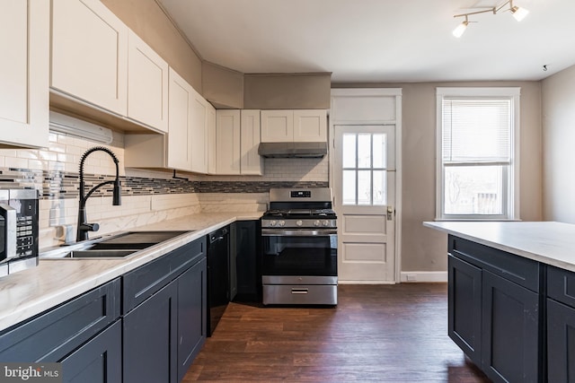 305 Drew St, Baltimore, MD 21224 - kitchen featuring dark wood finished floors, appliances with stainless steel finishes, under cabinet range hood, white cabinetry, and a sink