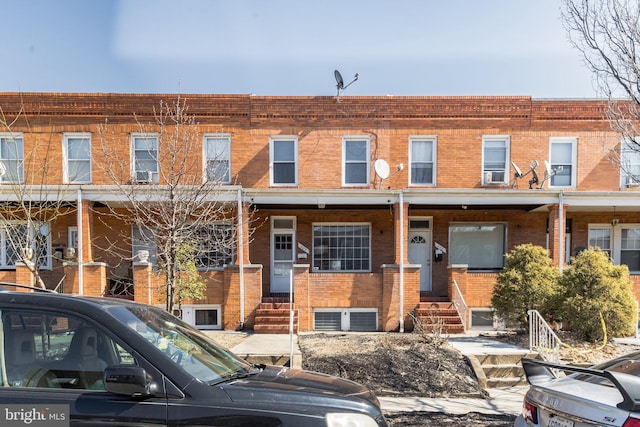 view of property with entry steps, brick siding, and cooling unit