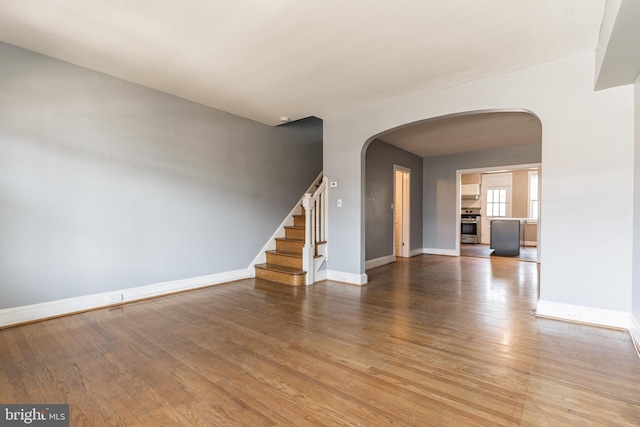 305 Drew St, Baltimore, MD 21224 - empty room with light wood-type flooring, arched walkways, stairway, and baseboards