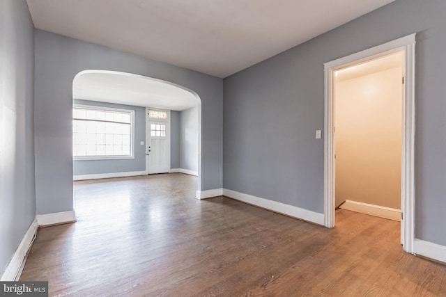 305 Drew St, Baltimore, MD 21224 - spare room featuring arched walkways, wood finished floors, and baseboards