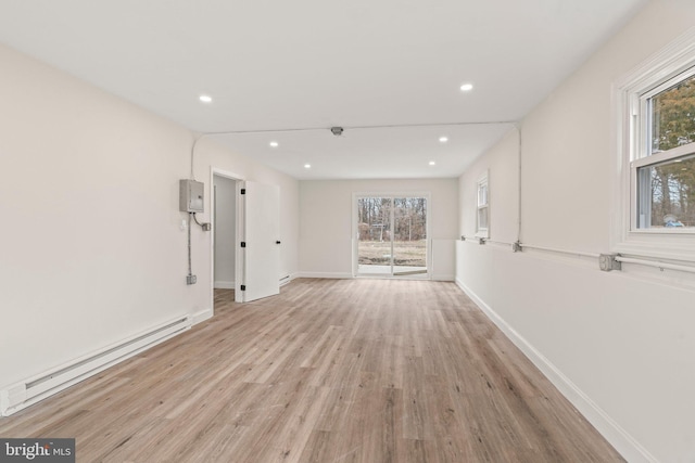 unfurnished living room featuring a baseboard heating unit, light wood-type flooring, baseboards, and recessed lighting