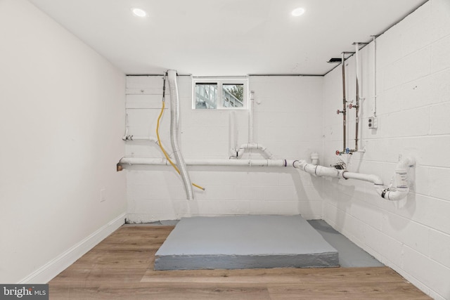 basement with recessed lighting, concrete block wall, baseboards, and wood finished floors