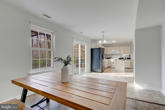 unfurnished dining area with light wood-type flooring, baseboards, and visible vents