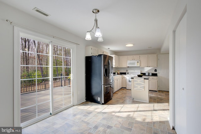 kitchen with visible vents, hanging light fixtures, a kitchen island, white appliances, and baseboards