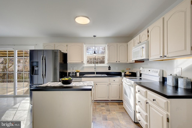 kitchen with white appliances, stone finish floor, dark countertops, and a sink