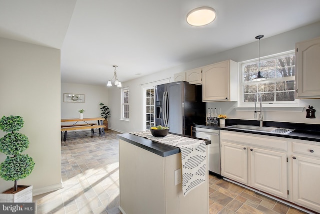 kitchen featuring appliances with stainless steel finishes, dark countertops, a sink, and pendant lighting