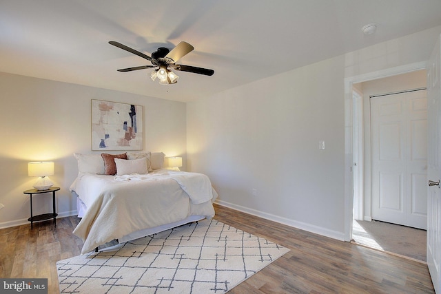 bedroom with light wood-type flooring, ceiling fan, and baseboards