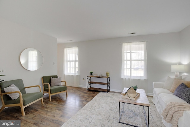 living room with baseboards, visible vents, and wood finished floors