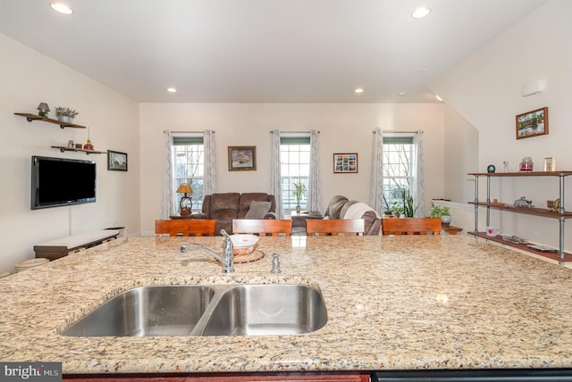 kitchen with light stone counters, recessed lighting, a sink, dishwasher, and open floor plan