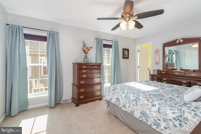 bedroom featuring visible vents, light colored carpet, baseboards, and ceiling fan