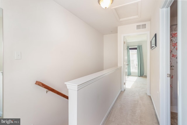 hall featuring an upstairs landing, attic access, light carpet, and visible vents