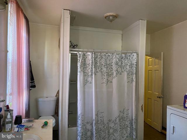 bathroom featuring toilet, washer / dryer, shower / tub combo with curtain, and vanity