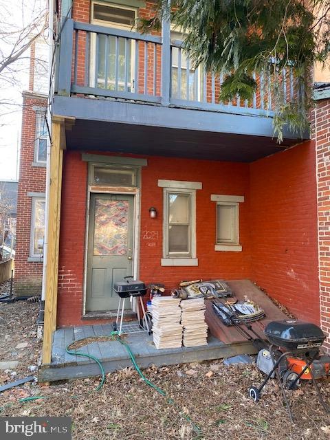 property entrance with brick siding and a balcony