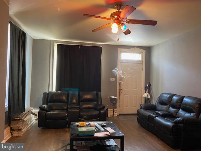 living room featuring baseboards, a ceiling fan, and wood finished floors