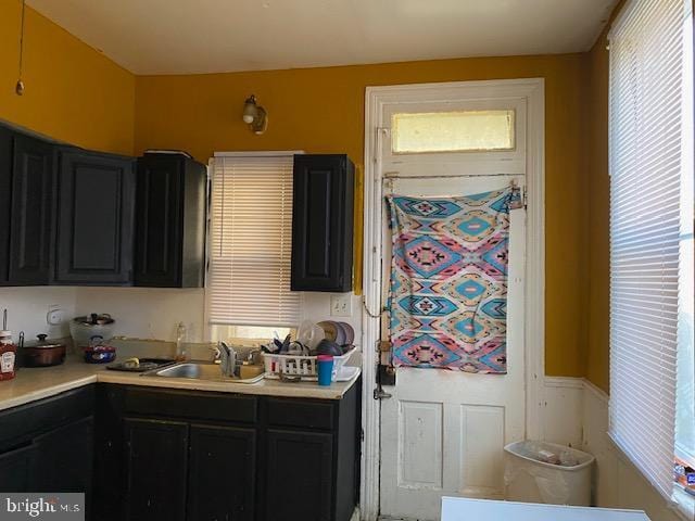 kitchen featuring light countertops, a sink, and dark cabinets