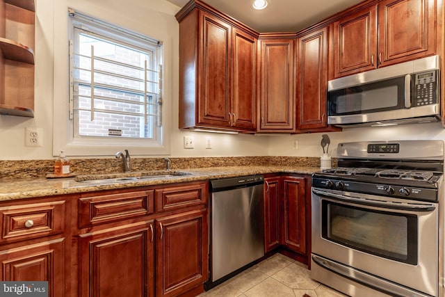 kitchen with light tile patterned floors, appliances with stainless steel finishes, light stone counters, a sink, and recessed lighting