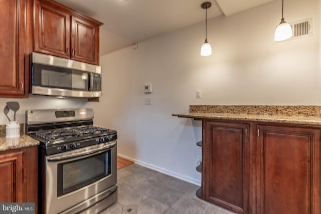 kitchen featuring baseboards, appliances with stainless steel finishes, light stone counters, and pendant lighting