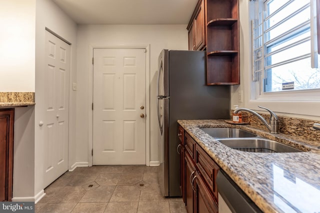 kitchen featuring light tile patterned floors, open shelves, a sink, light stone countertops, and dishwasher