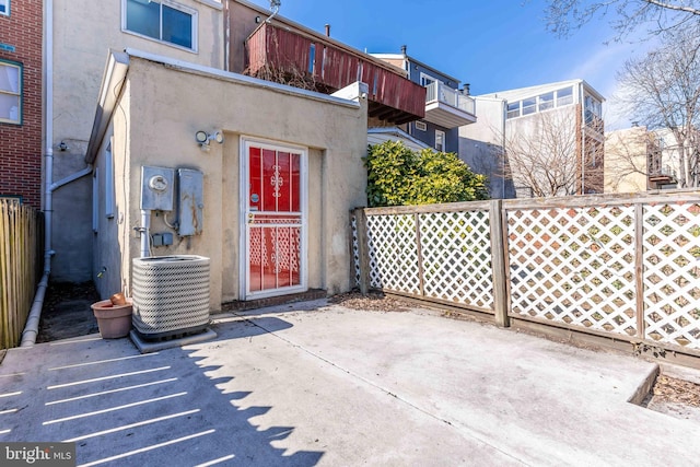 exterior space featuring a patio area, stucco siding, fence, and central air condition unit