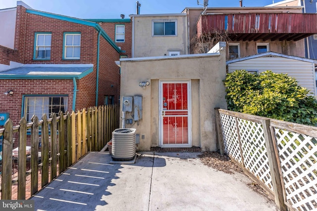 rear view of property featuring fence, cooling unit, and stucco siding