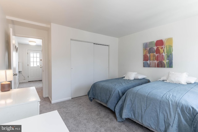 bedroom with light carpet, baseboards, and a closet