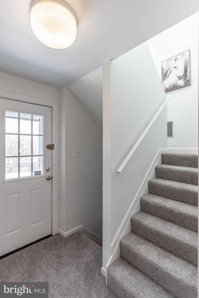 doorway with carpet floors, stairway, visible vents, and baseboards