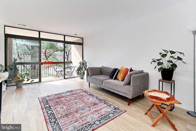 living area featuring a wall of windows, wood finished floors, and visible vents