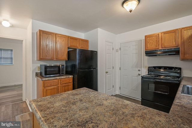 kitchen featuring black appliances, under cabinet range hood, dark wood-style floors, and brown cabinetry