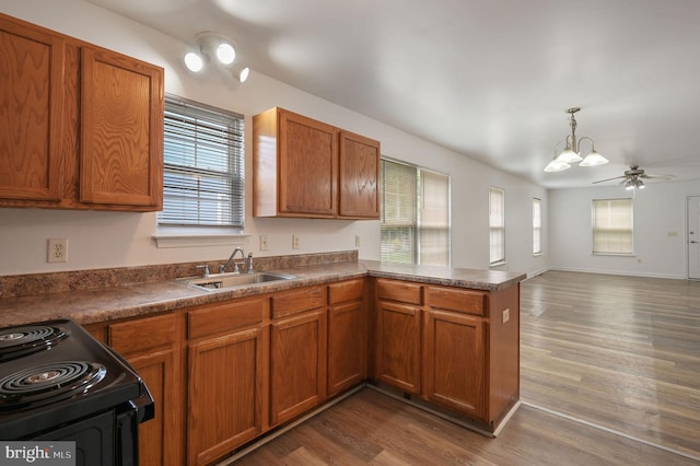 kitchen with electric range, a chandelier, a sink, a peninsula, and dark wood finished floors