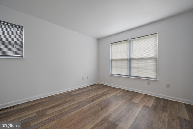 empty room featuring dark wood-type flooring and baseboards