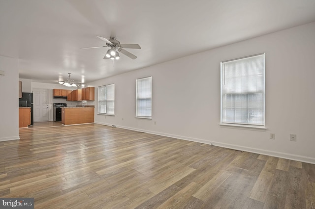 unfurnished living room with ceiling fan, light wood-style floors, and baseboards