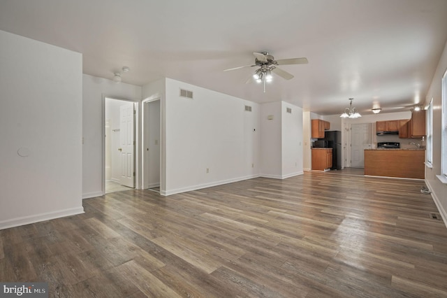 unfurnished living room with a ceiling fan, dark wood-style flooring, a chandelier, and baseboards