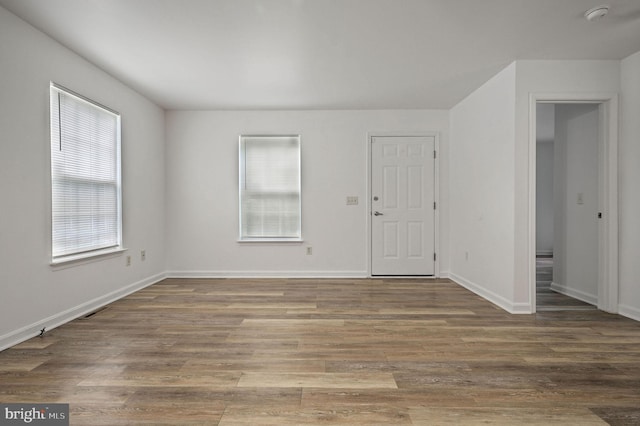 empty room with a smoke detector, wood finished floors, and baseboards