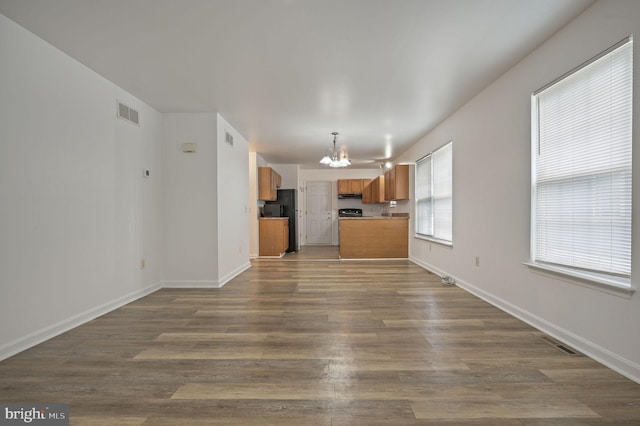 unfurnished living room with a chandelier, dark wood-style floors, and baseboards