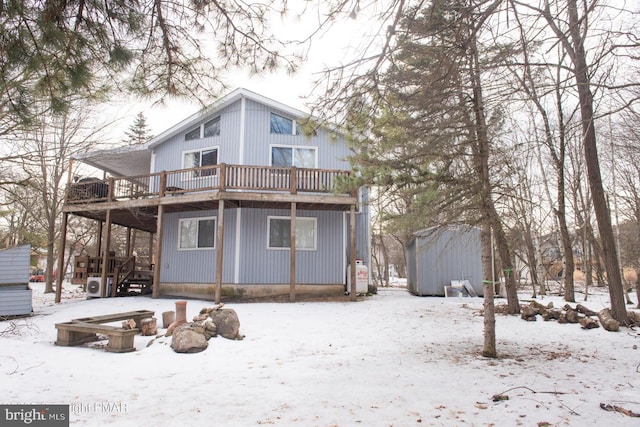 snow covered back of property featuring a deck and an outbuilding