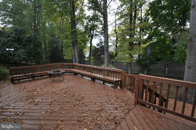 wooden terrace featuring an outdoor fire pit and a fenced backyard