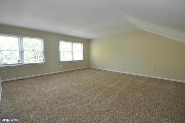 interior space with baseboards, visible vents, vaulted ceiling, and carpet flooring