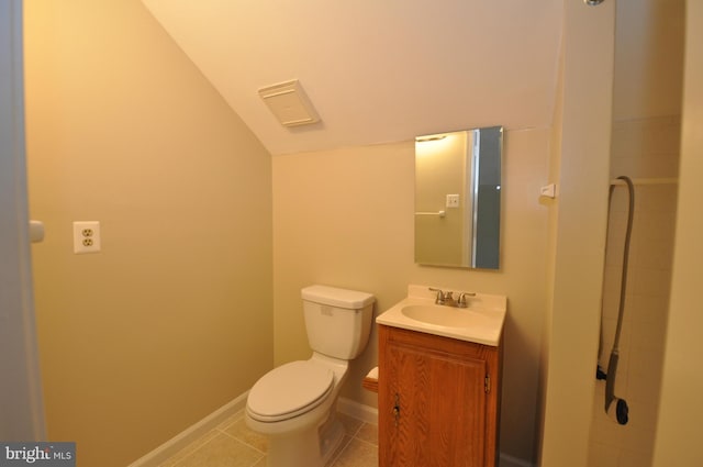 bathroom with lofted ceiling, toilet, vanity, baseboards, and tile patterned floors