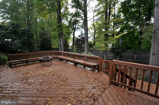 wooden terrace with a fenced backyard and a fire pit