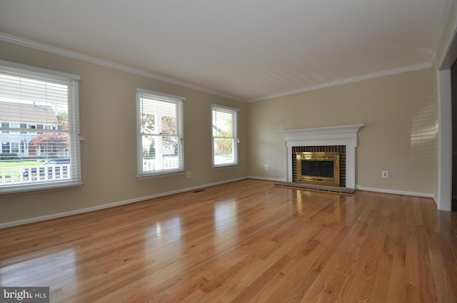 unfurnished living room featuring baseboards, visible vents, ornamental molding, light wood-type flooring, and a fireplace