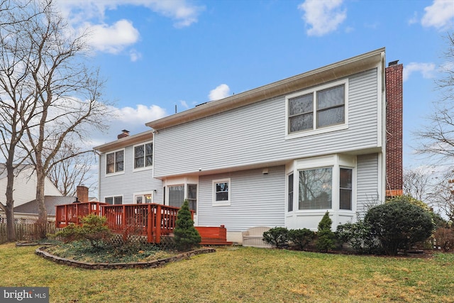 back of property with a chimney, a lawn, and a wooden deck