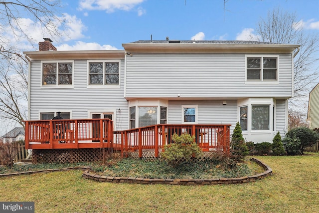 rear view of property with a lawn, a chimney, and a wooden deck