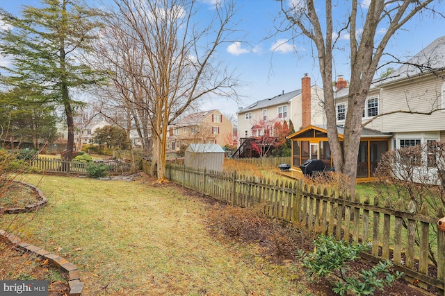 view of yard featuring a residential view, a fenced backyard, and a sunroom