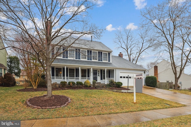 colonial home featuring a chimney, a porch, concrete driveway, an attached garage, and a front lawn